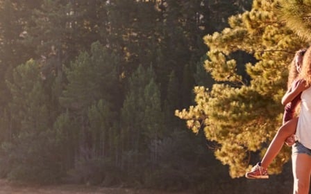 A man and woman walking in the woods.