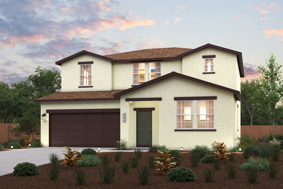 A house with a garage and bushes in front of it.