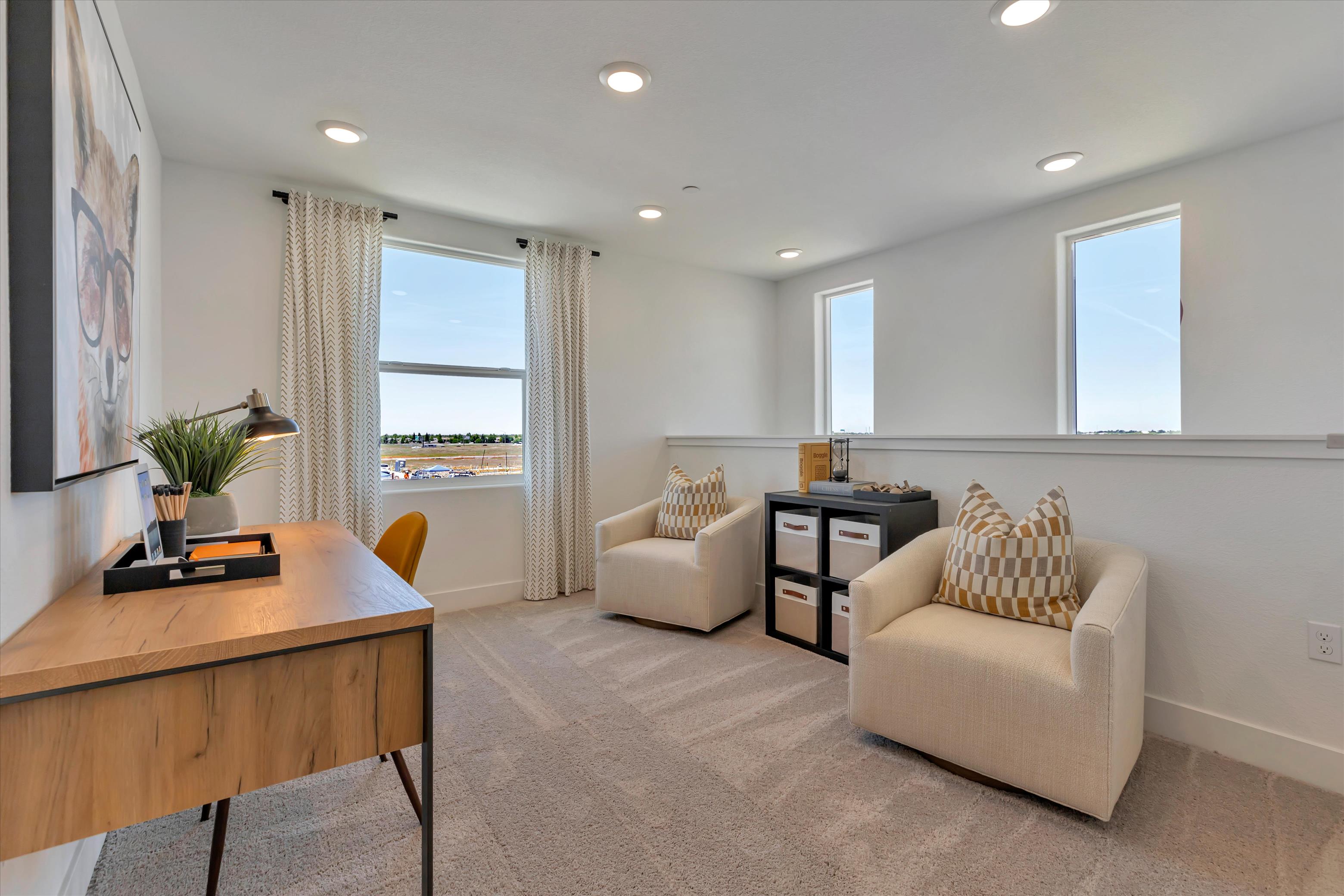 A living room with a desk and chairs.