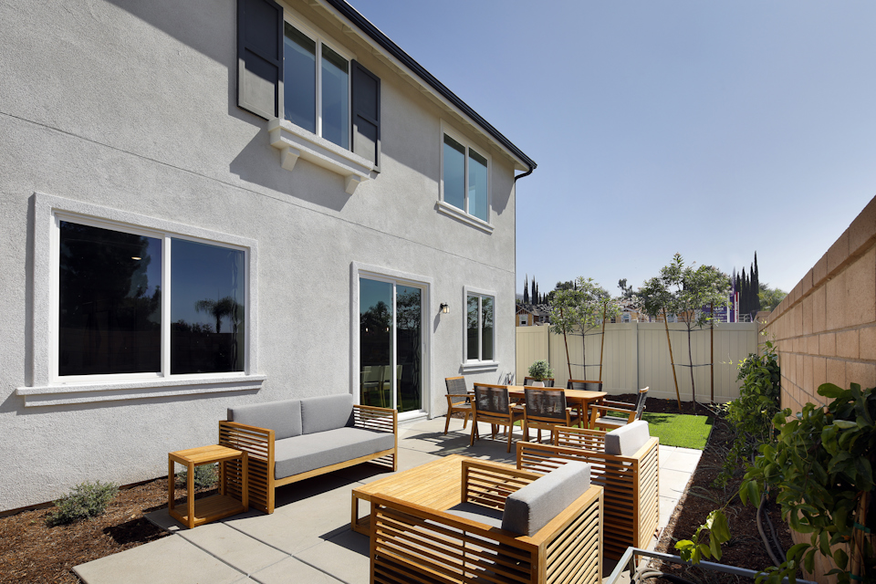 A patio with chairs and tables outside a house.