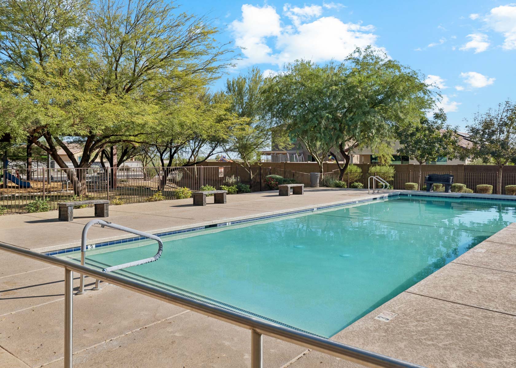 A swimming pool with trees and a fence around it.