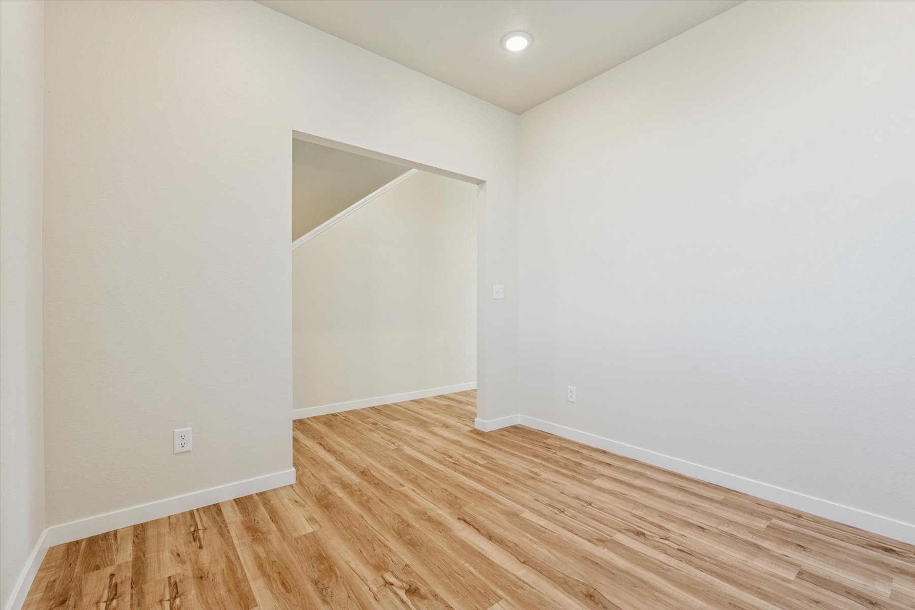 A room with a wood floor and a white wall.