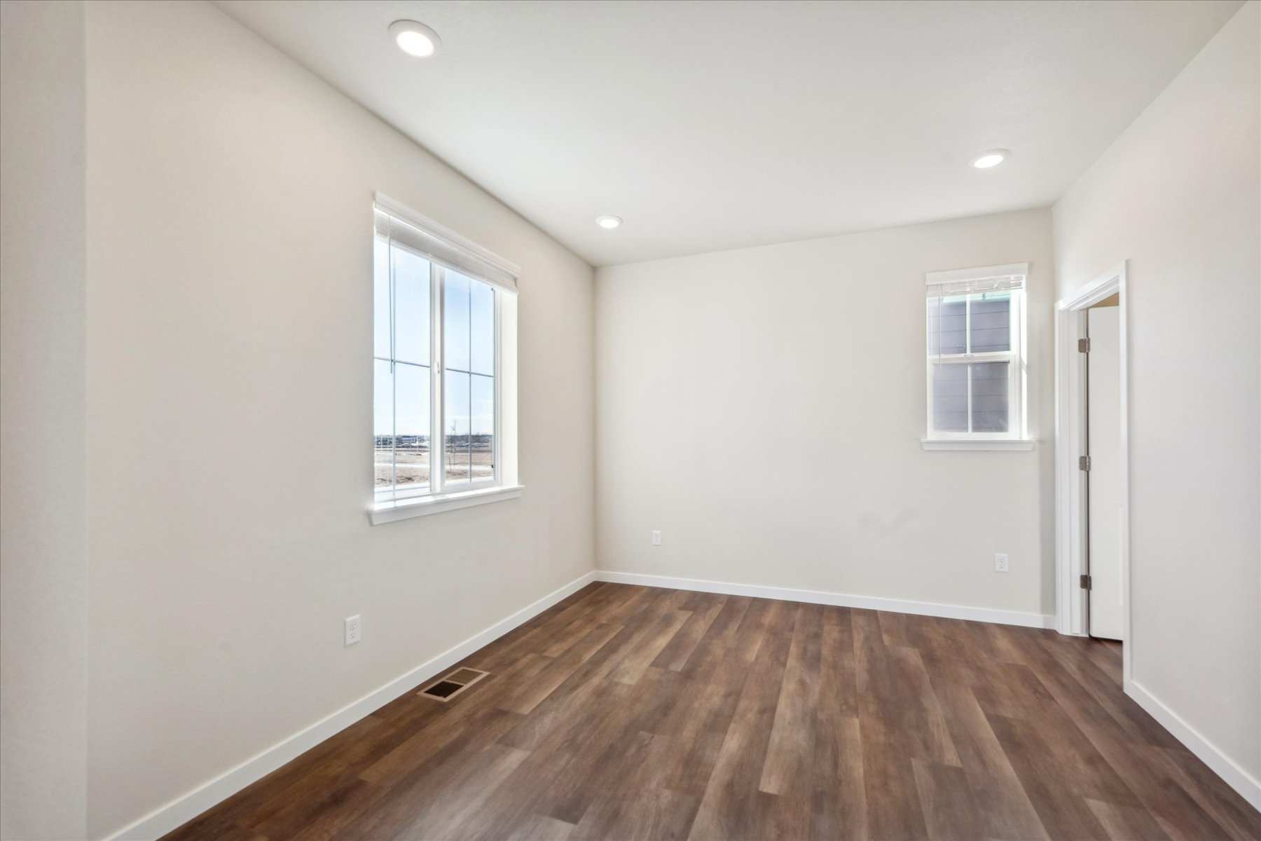 A room with a wood floor and windows.