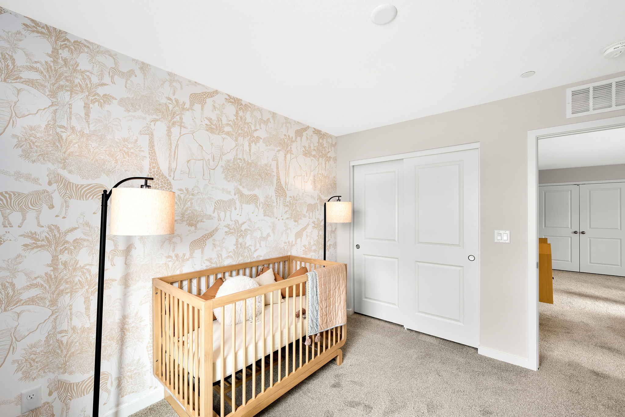 A room with a crib and a wall with a wallpaper.