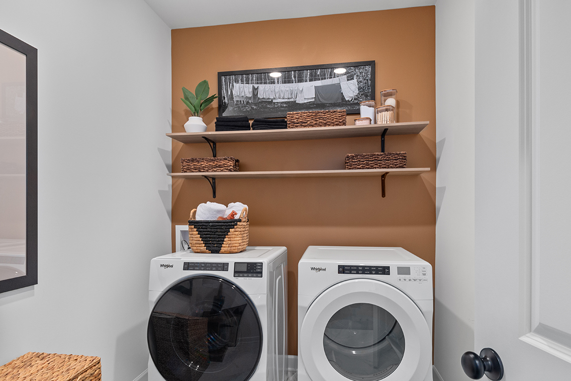 A room with a shelf and a washing machine.