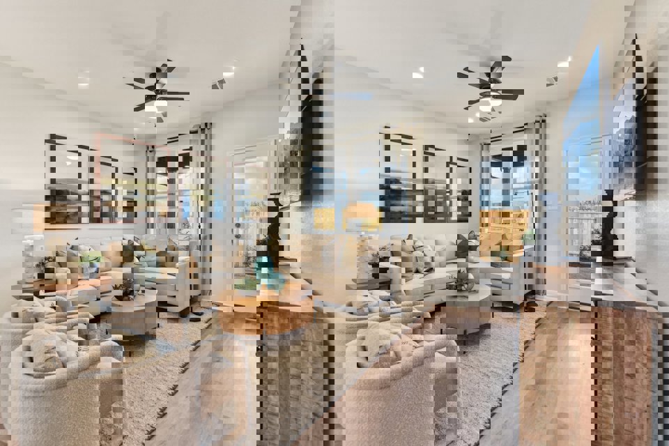 A living room with a large white couch and a wood floor.