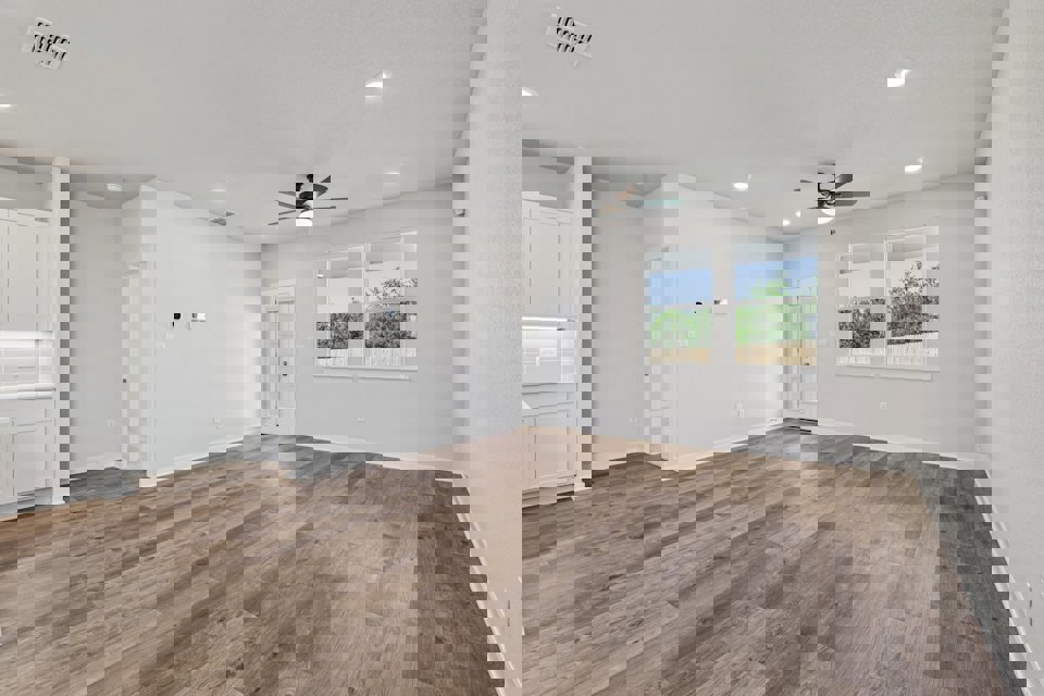 A large empty room with a wood floor and a ceiling fan.