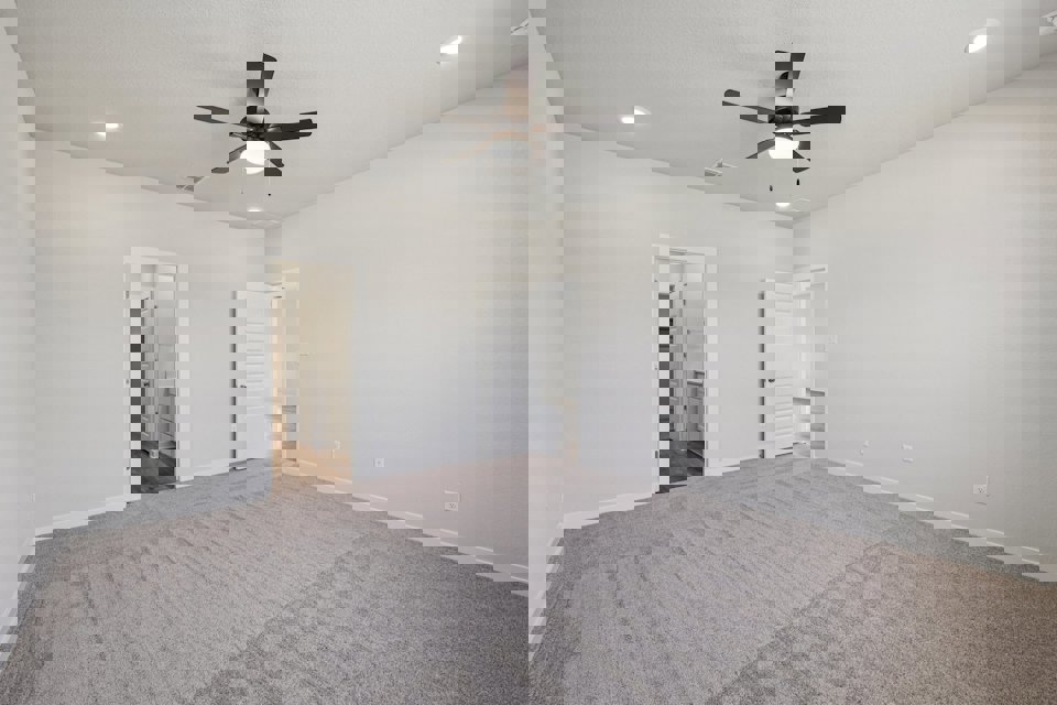 A room with a ceiling fan and a carpet.
