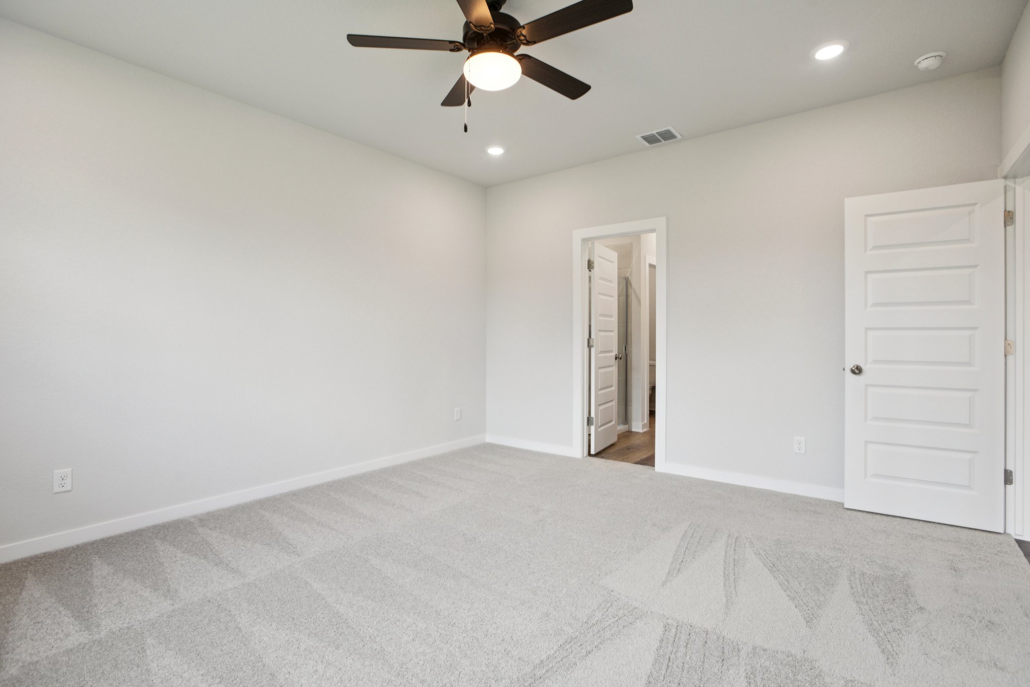 A room with a ceiling fan and a door.