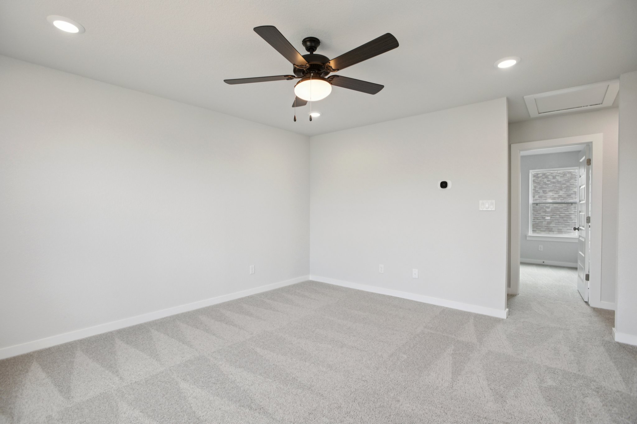 A room with a ceiling fan and a door.