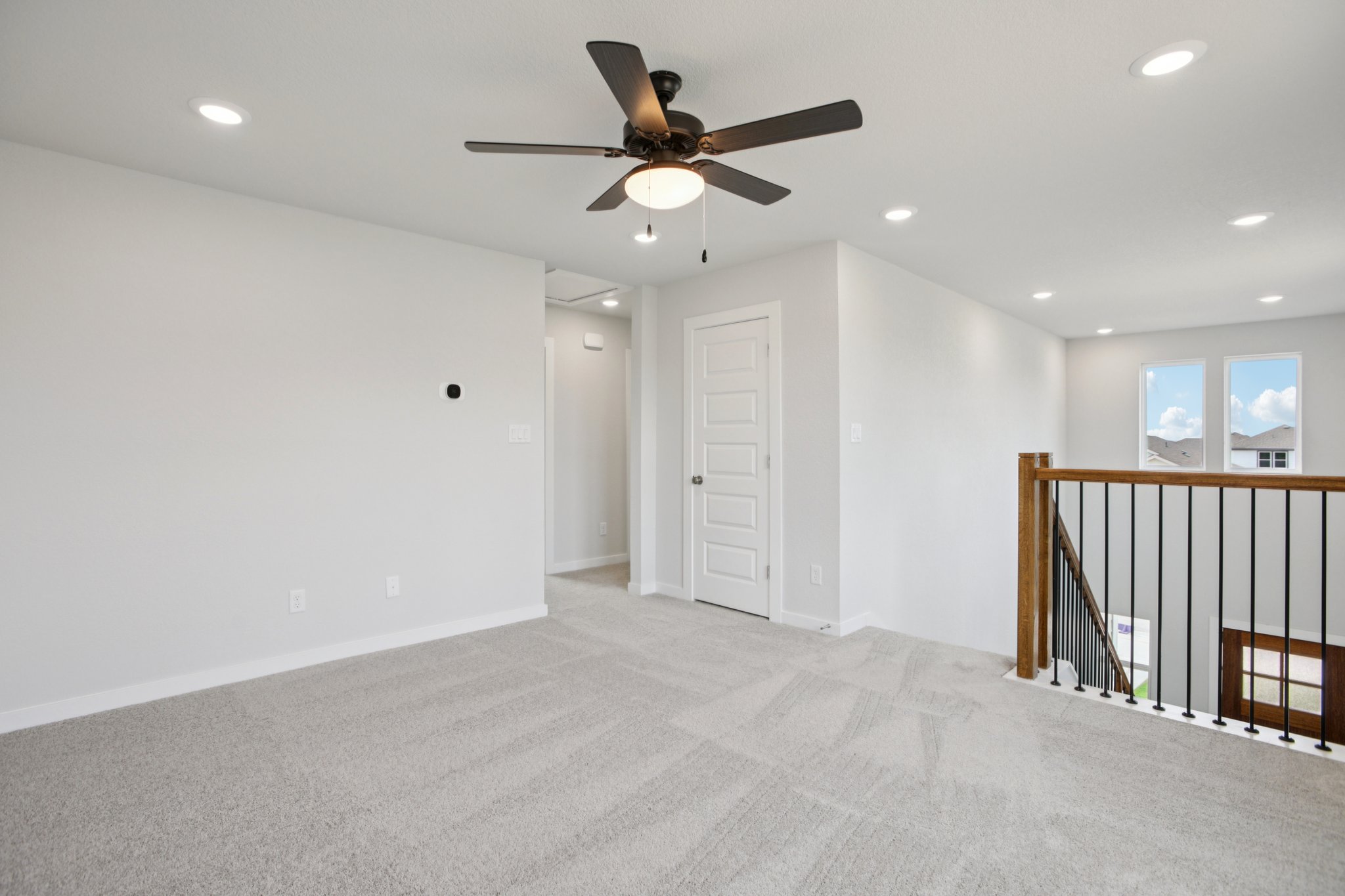 A room with a ceiling fan and a railing.