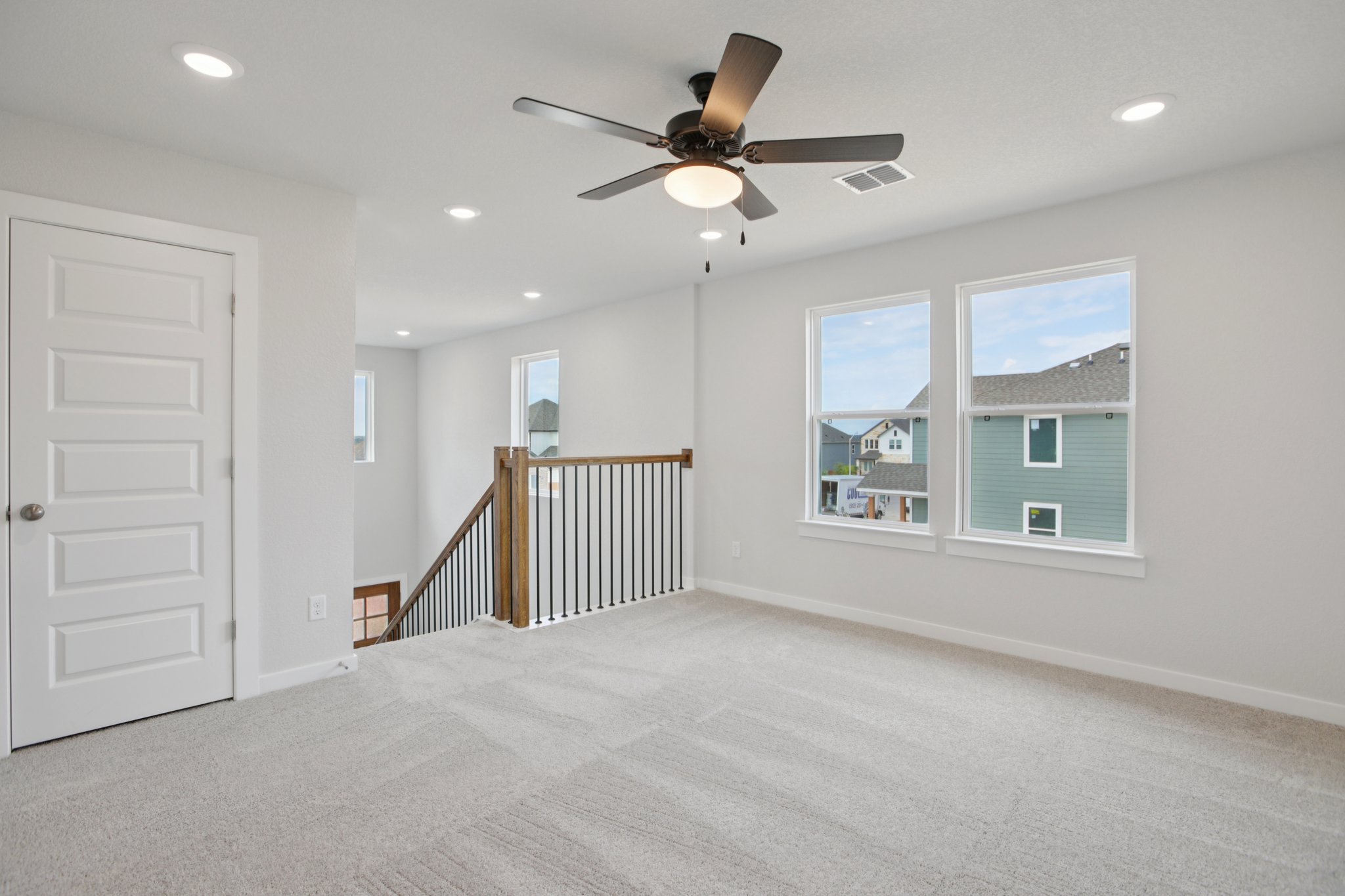 A room with a ceiling fan and a door with a window and a railing.