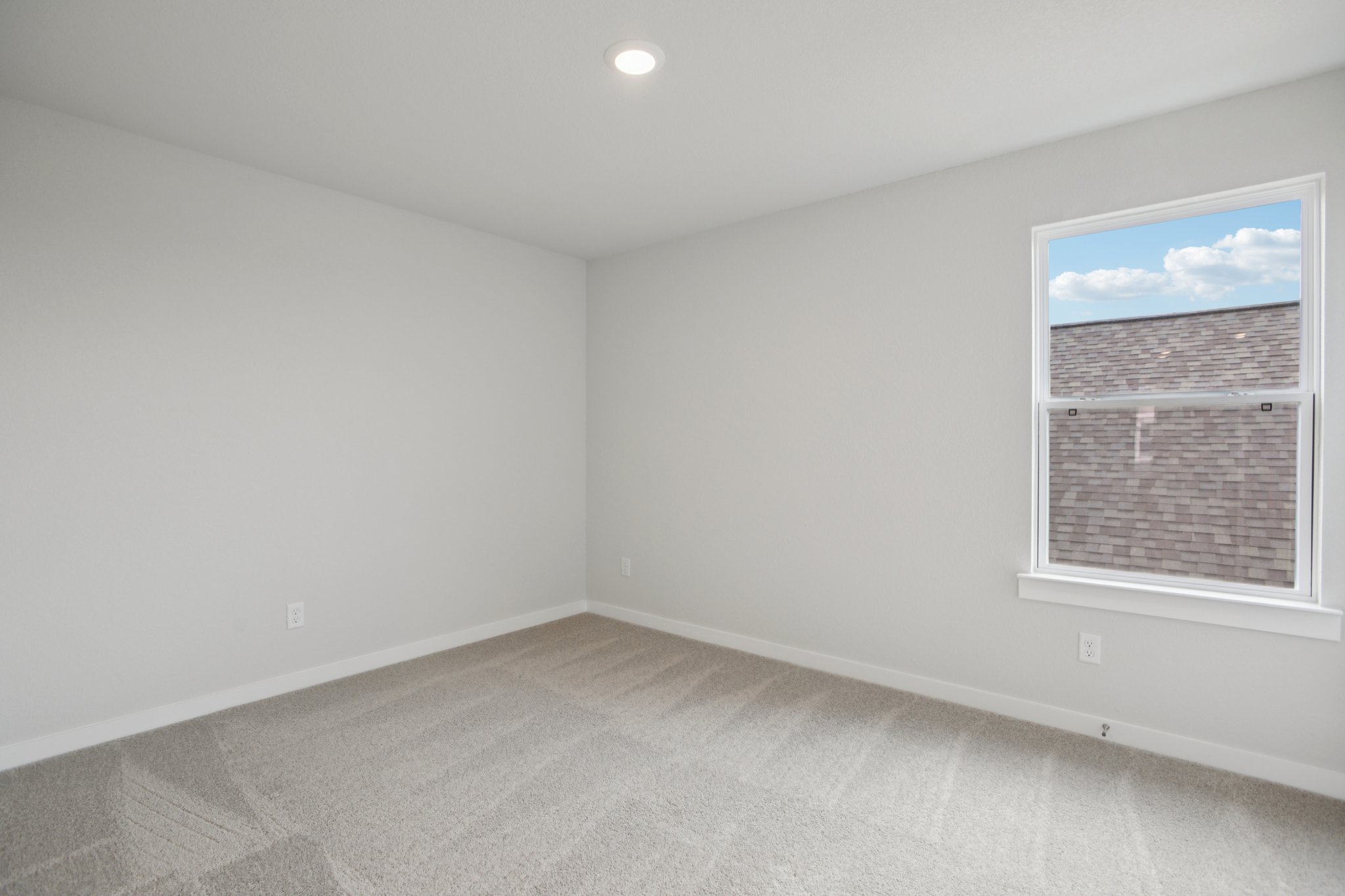 A room with a window and a white wall.