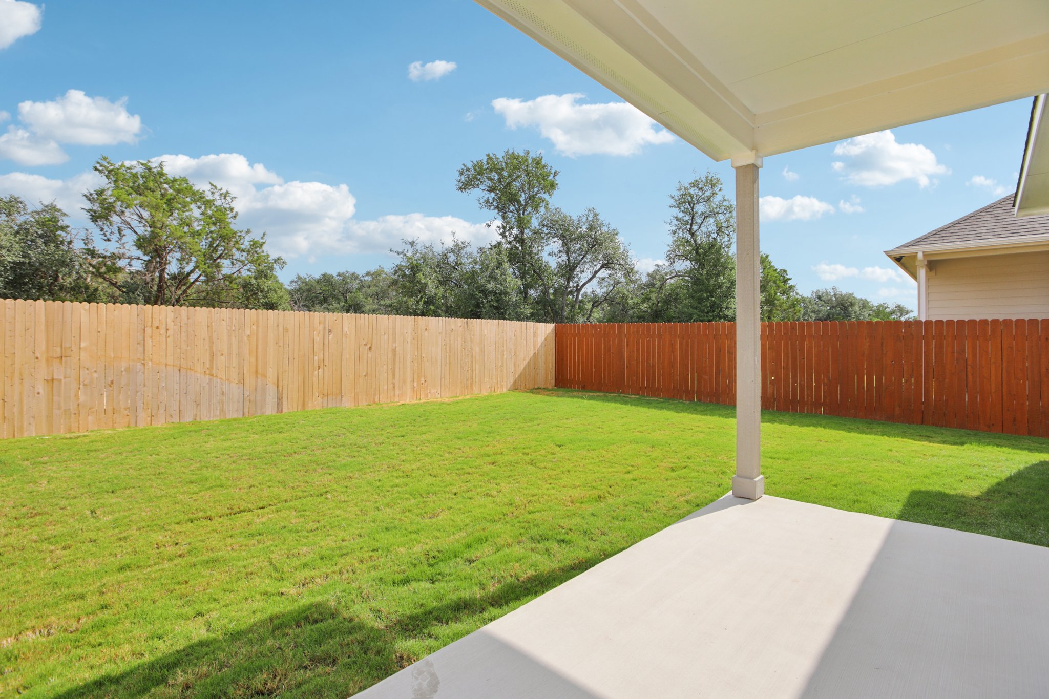 A backyard with a fence and a lawn.
