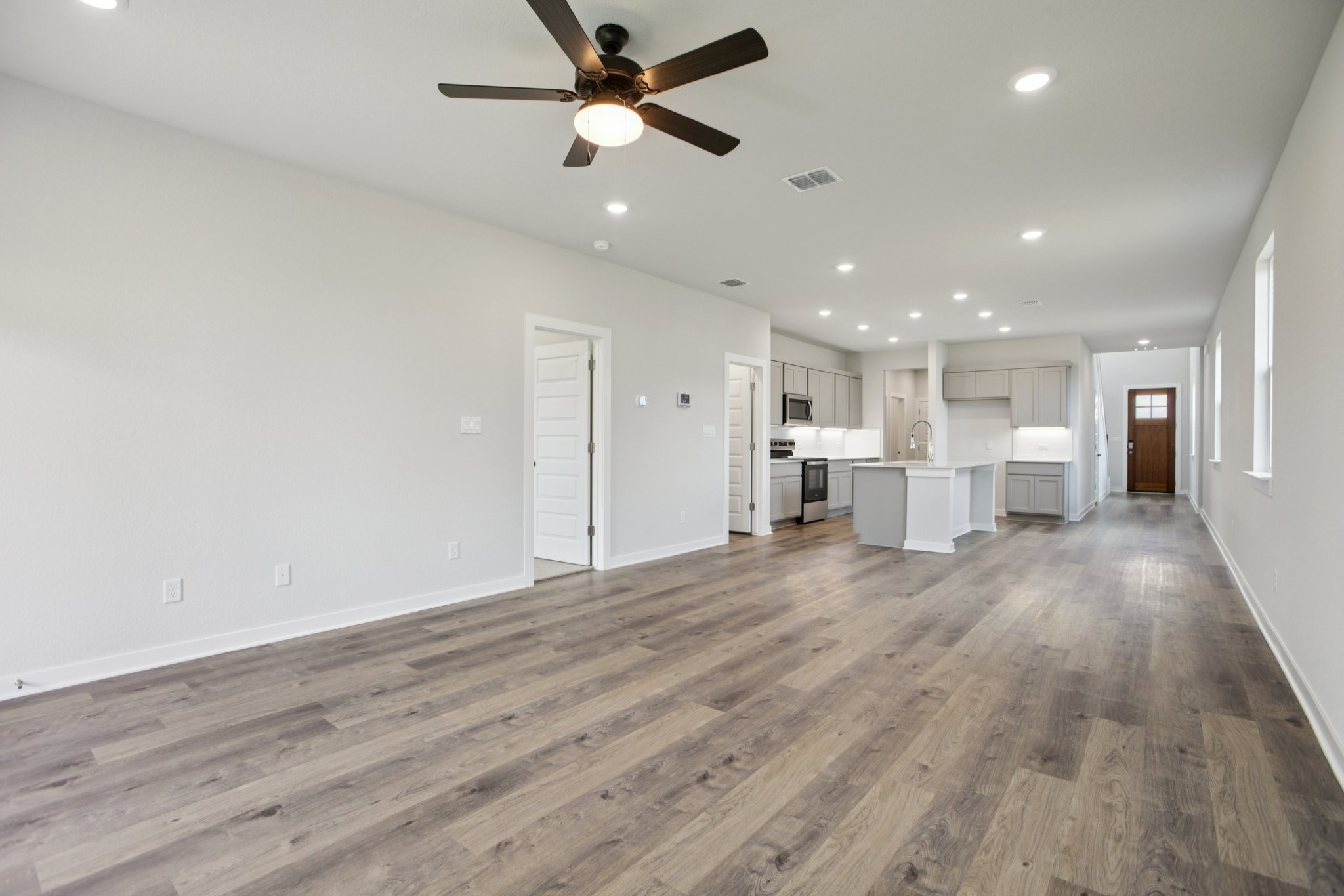 A large empty room with a wood floor and a ceiling fan.