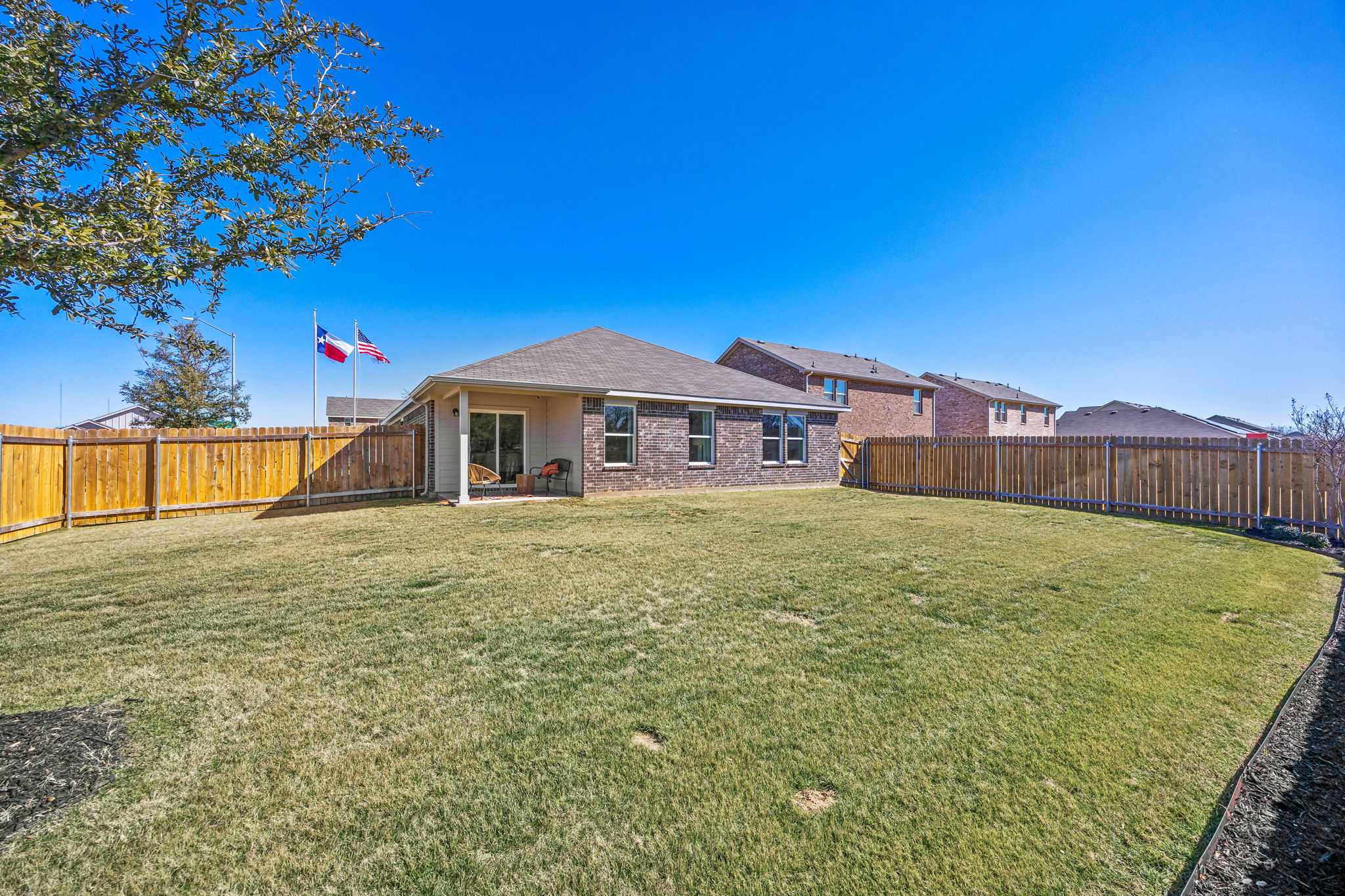 A house with a fence and a lawn in front of it.