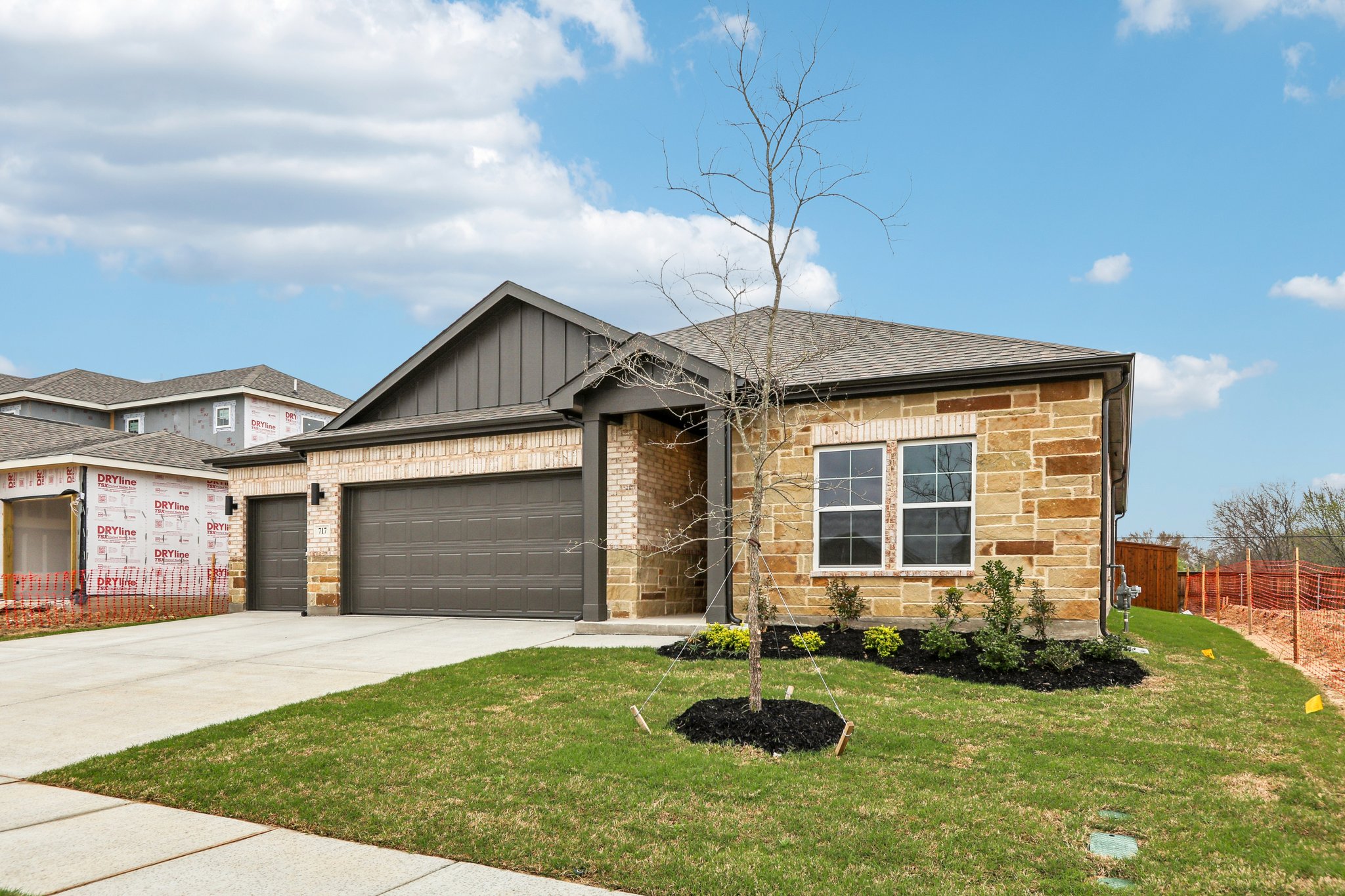 A house with a garage and a tree in the front.