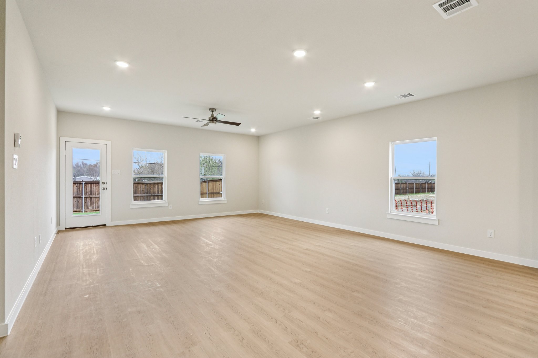 A large empty room with a wood floor and a ceiling fan.