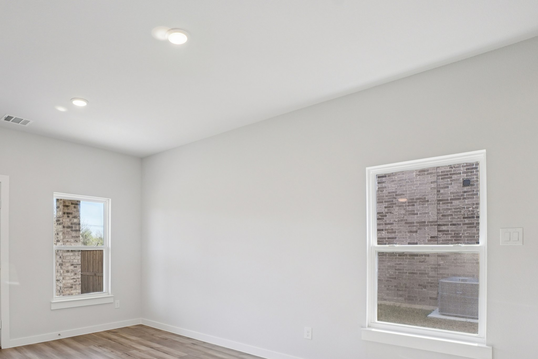 A room with a window and a wood floor.