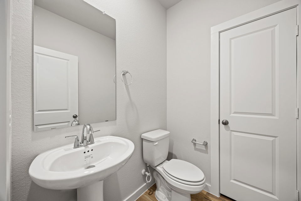 A bathroom with a sink toilet and mirror.