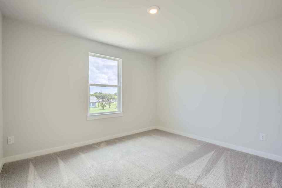 A room with a window and a white wall.