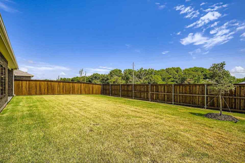 A fenced in yard with a wood fence and trees in the background.