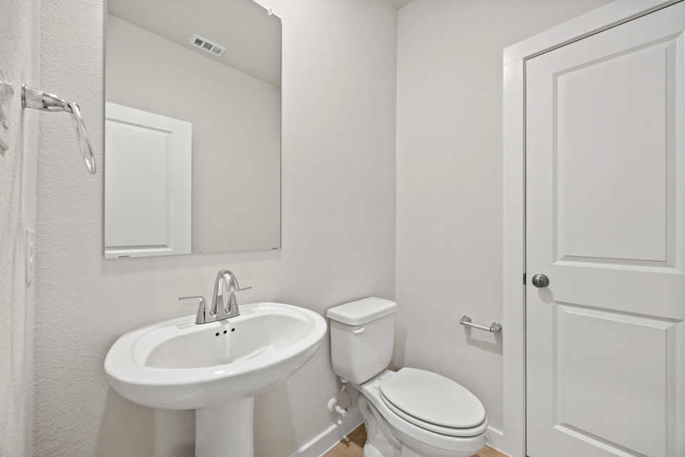 A bathroom with a sink toilet and mirror.