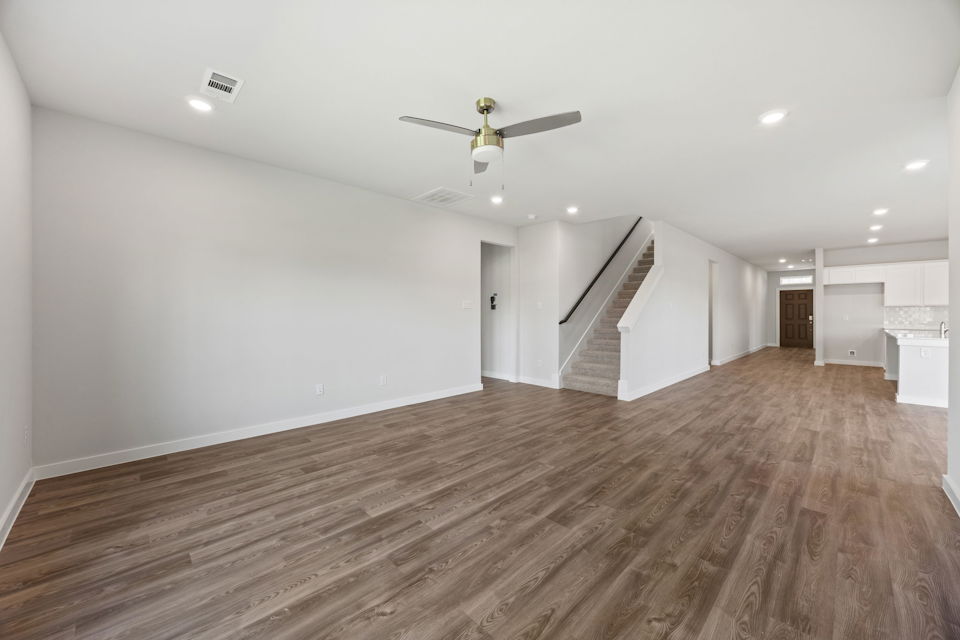 A large empty room with a wood floor and a staircase.