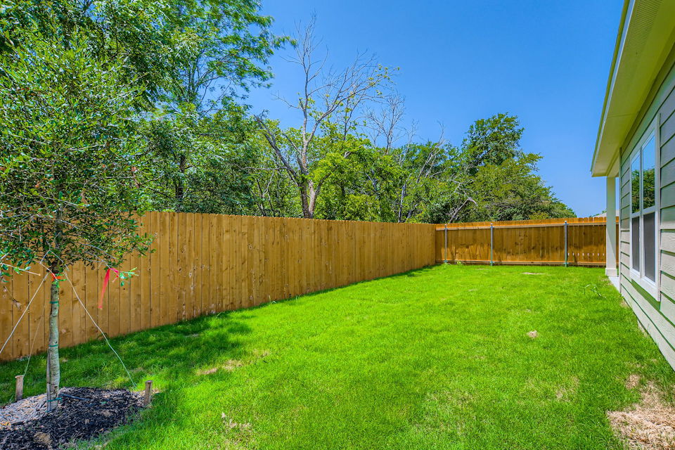 A fenced in yard with a wood fence and trees.