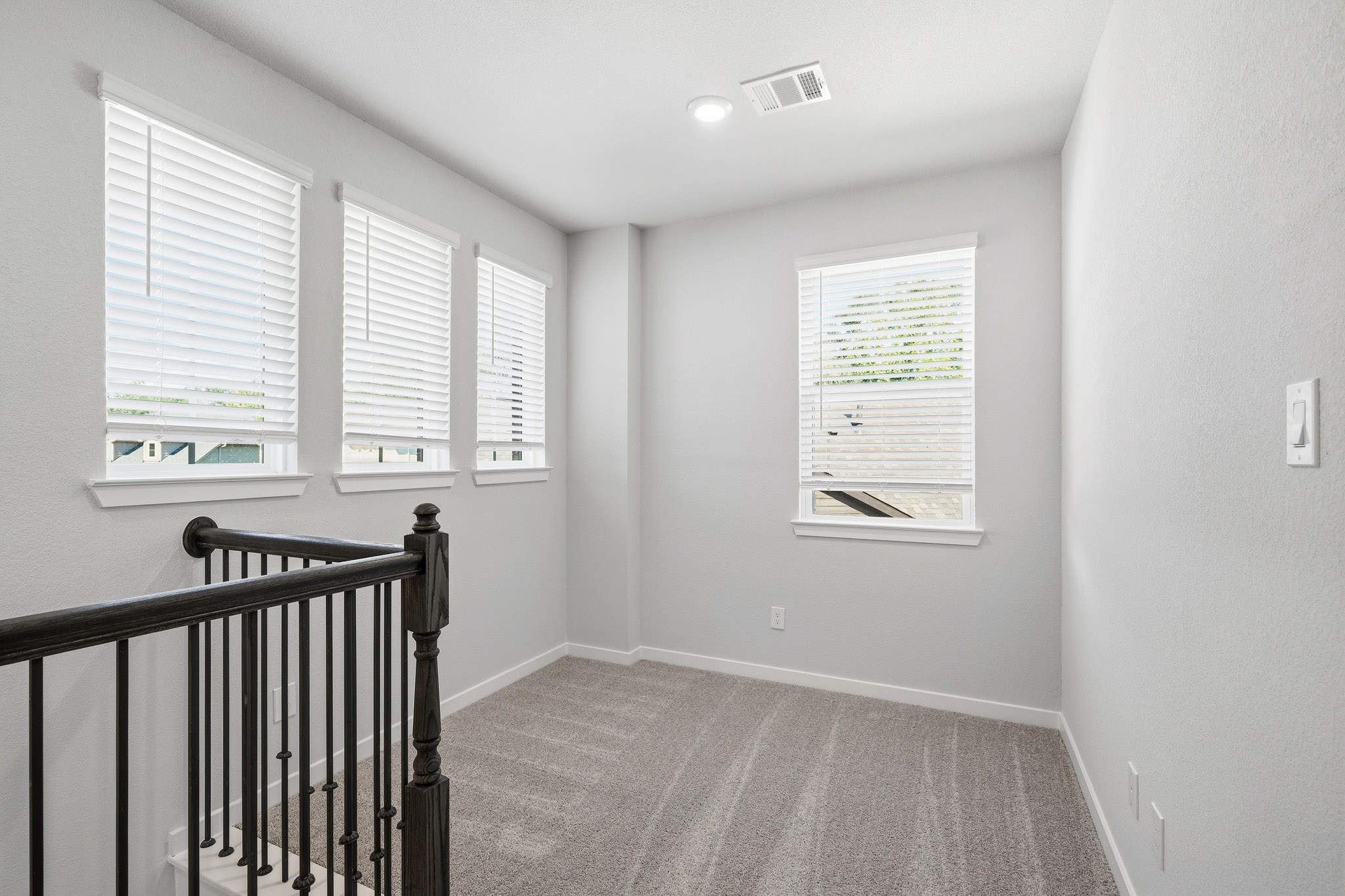 A hallway with a railing and a window.