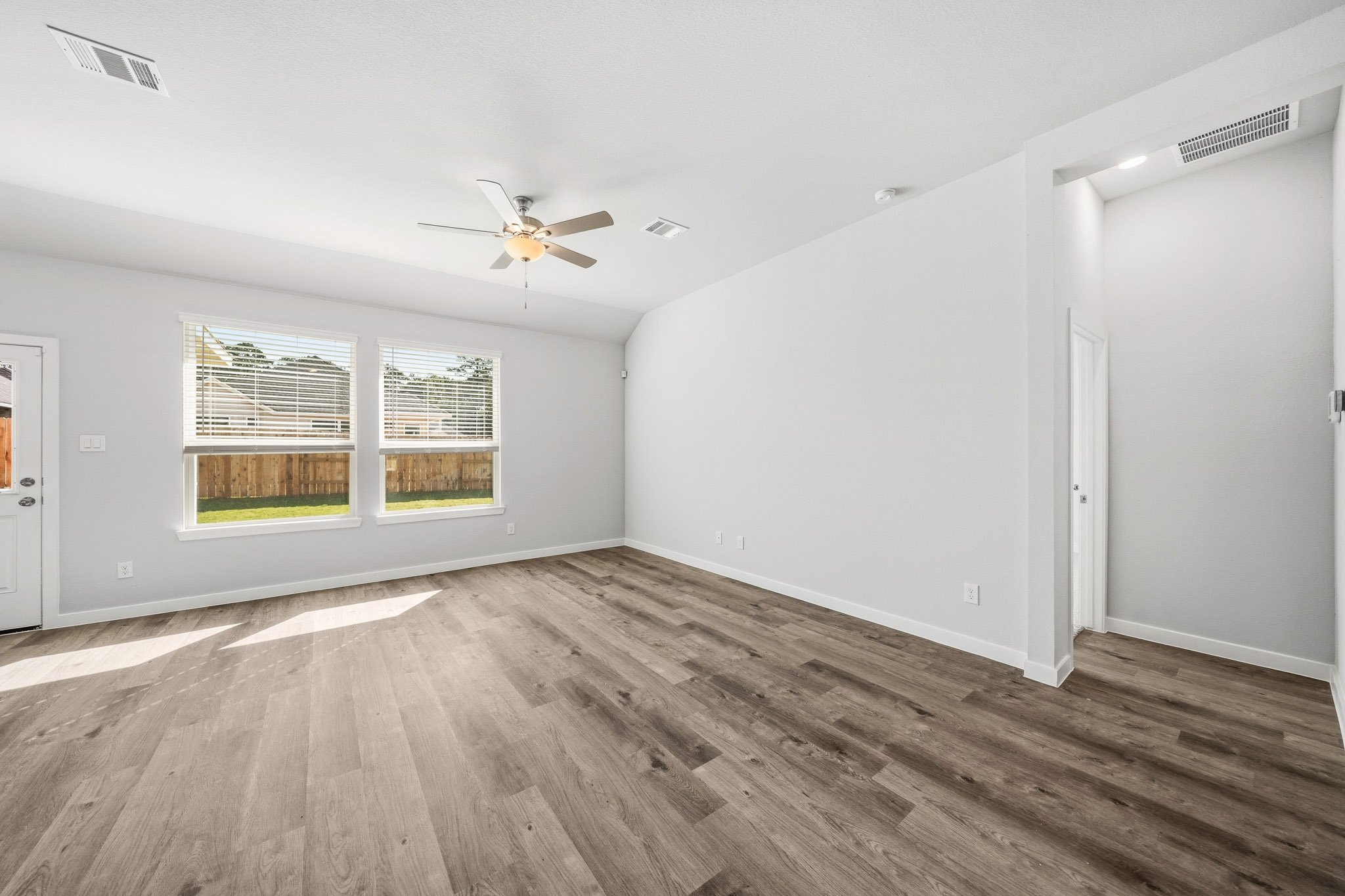 A room with a wood floor and a ceiling fan.