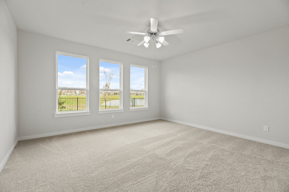 A room with a ceiling fan and a window with a view of the ocean.