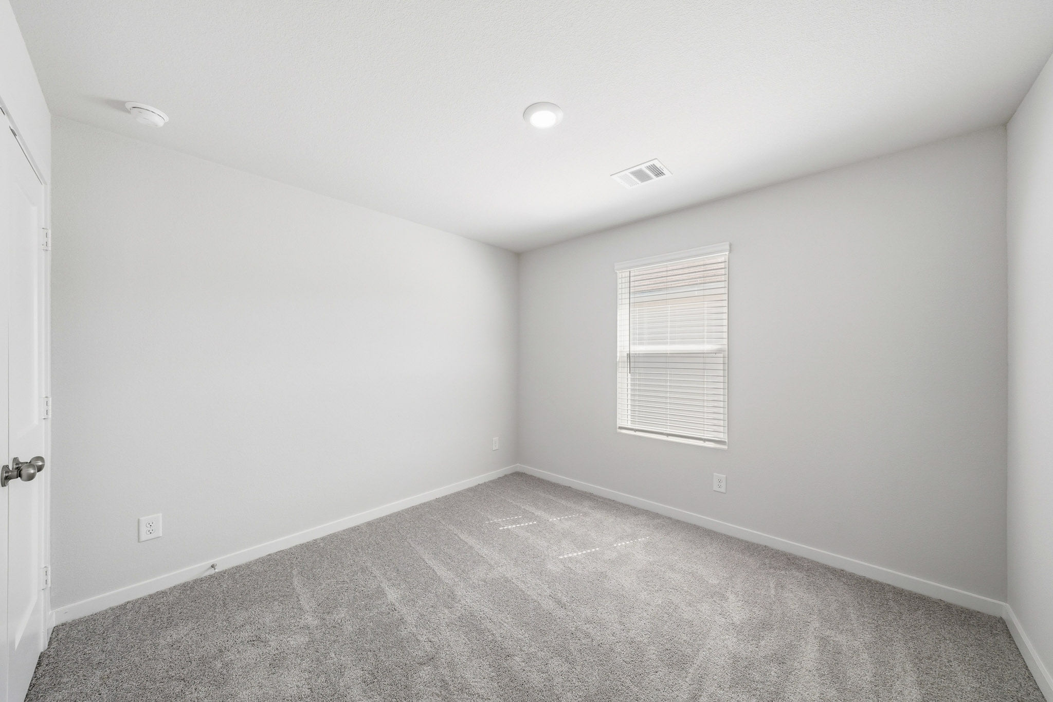 A room with a carpet and a door.