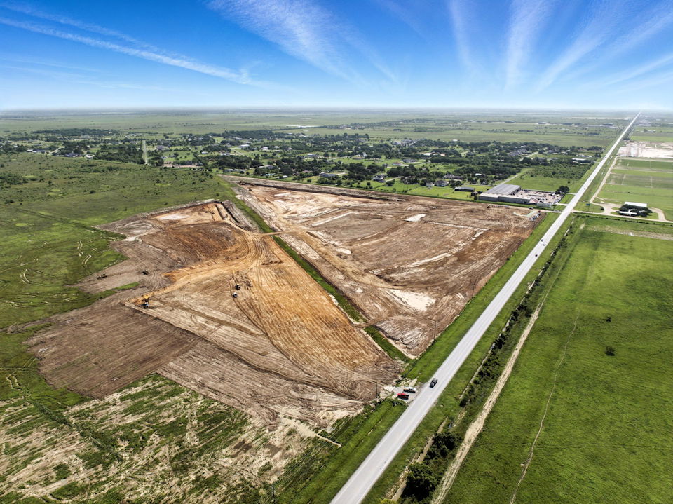 A road with a field and buildings.