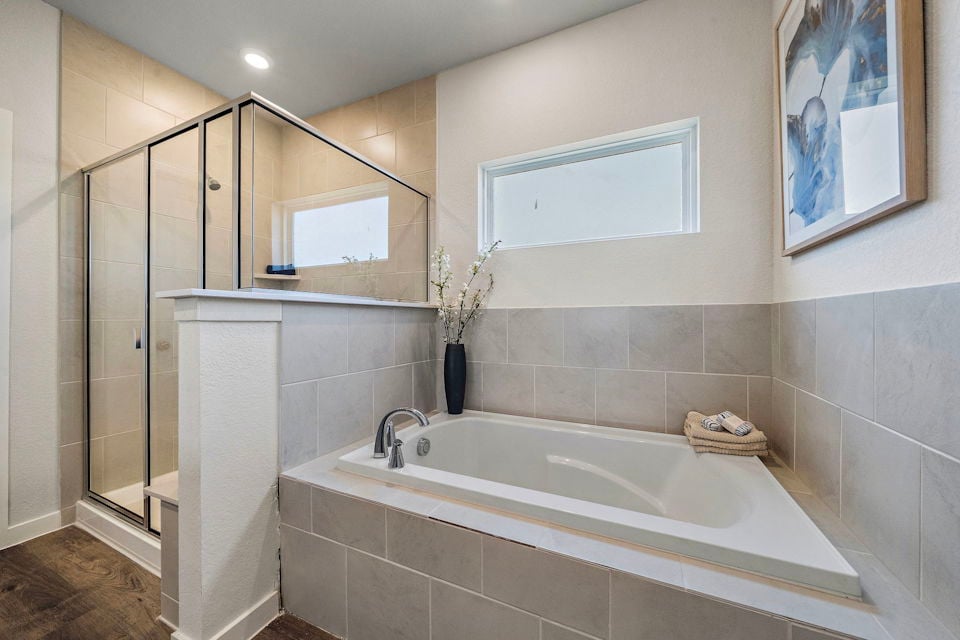 A bathroom with a tub and a vase of flowers.