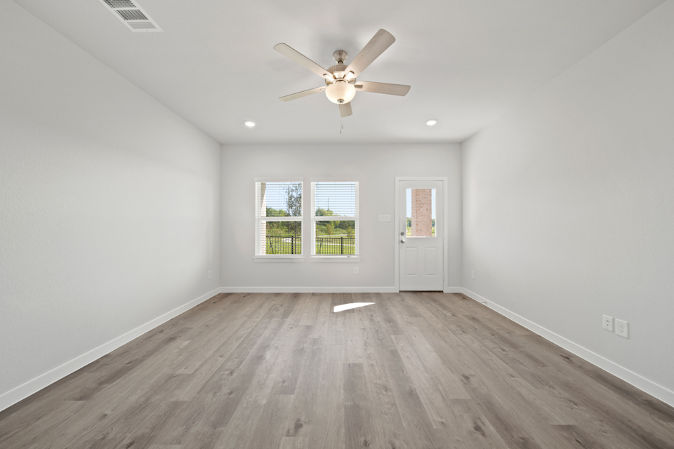A room with a ceiling fan and a wood floor.