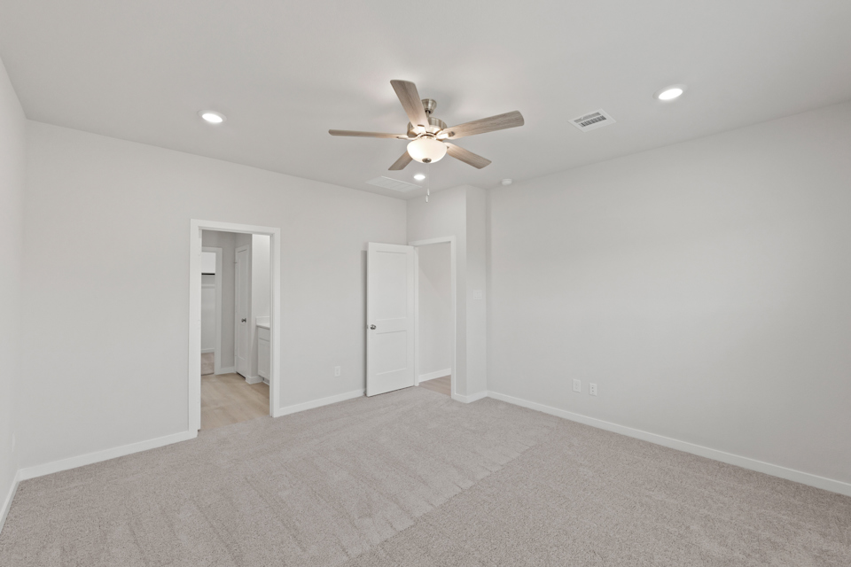 A room with a ceiling fan and a carpet.