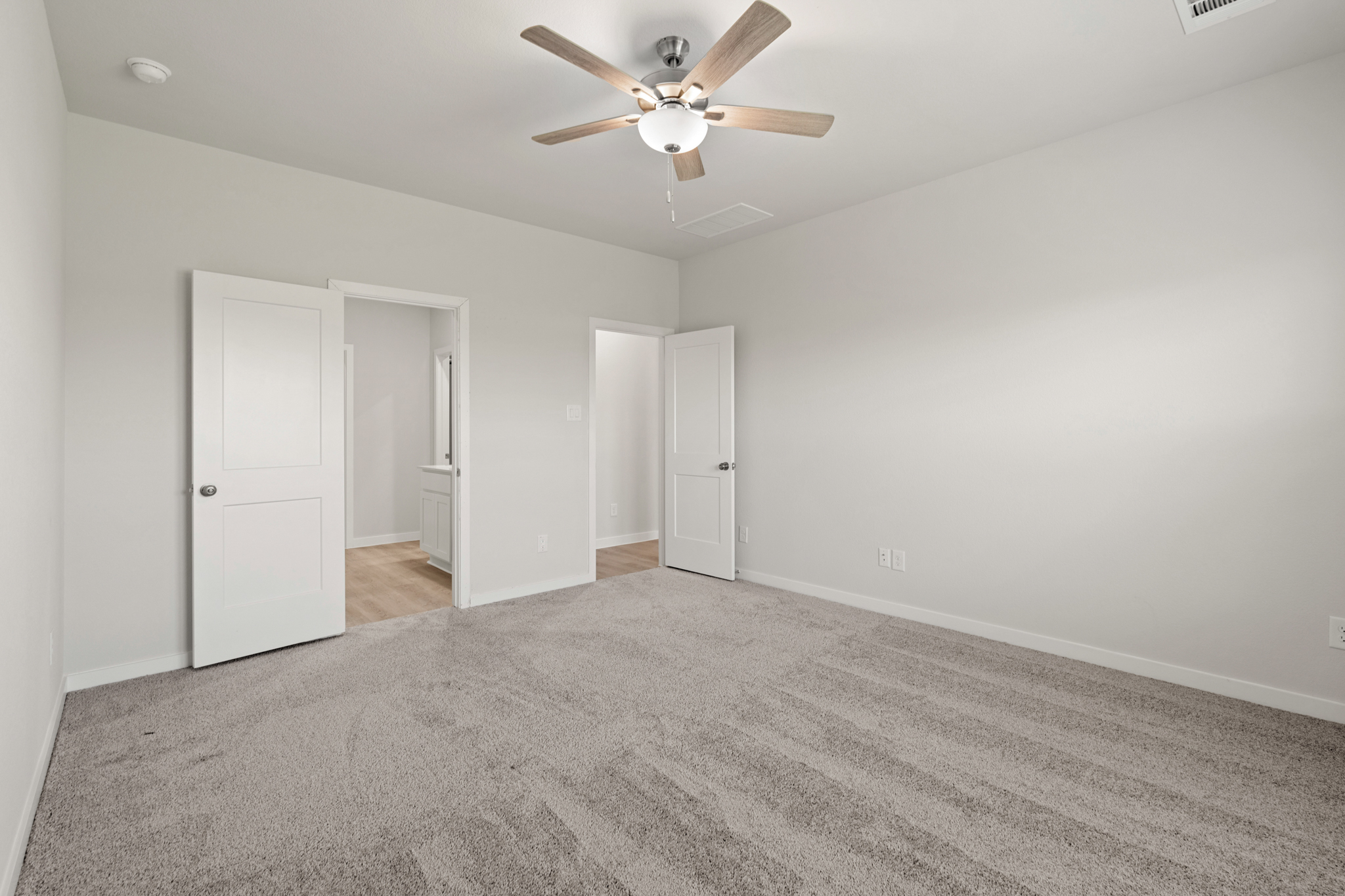 A room with a ceiling fan and white doors.