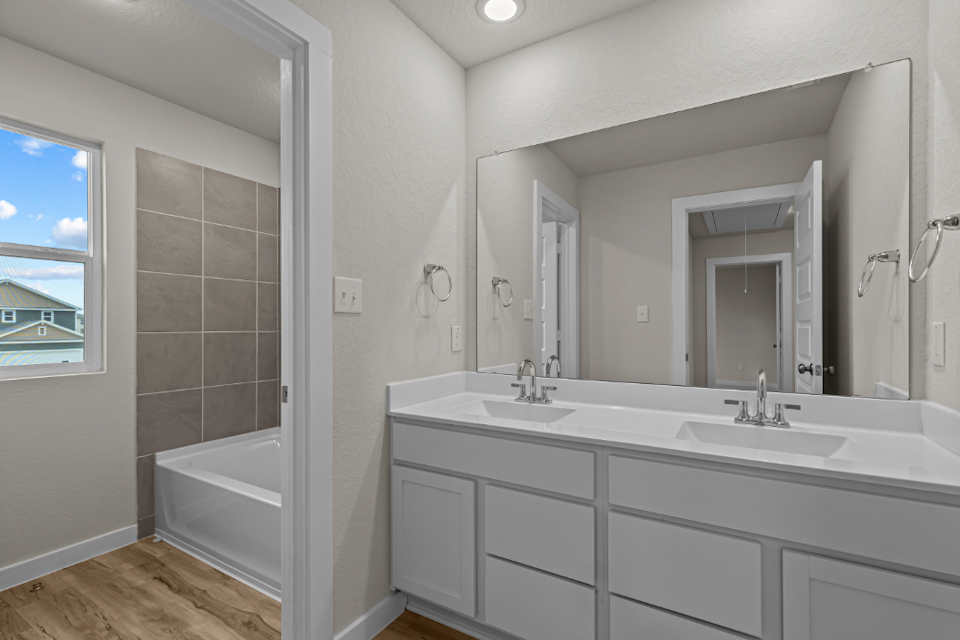 A bathroom with a tub sink and mirror.