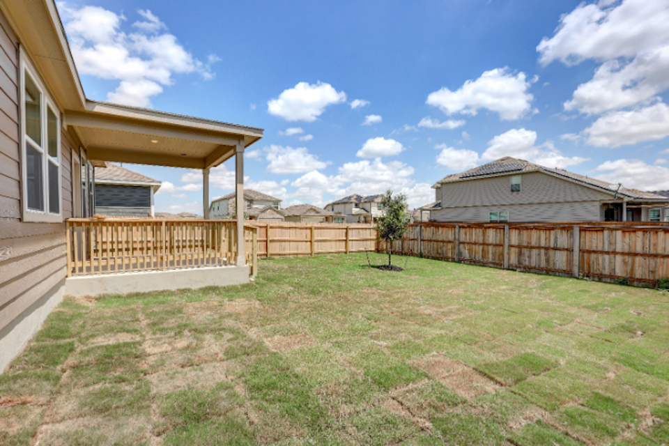 A backyard with a fence and a tree.