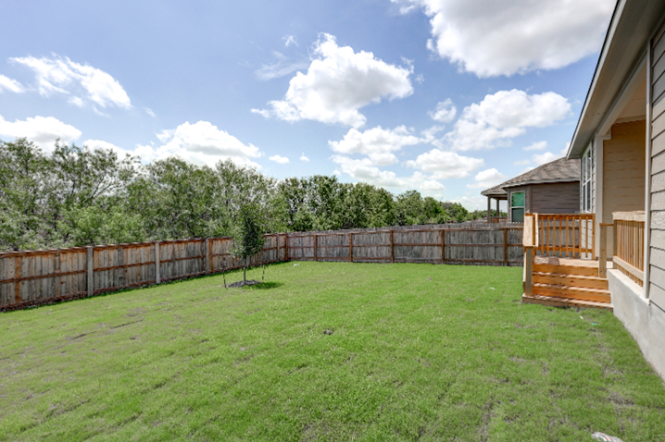 A fenced in yard with a house and trees in the background.