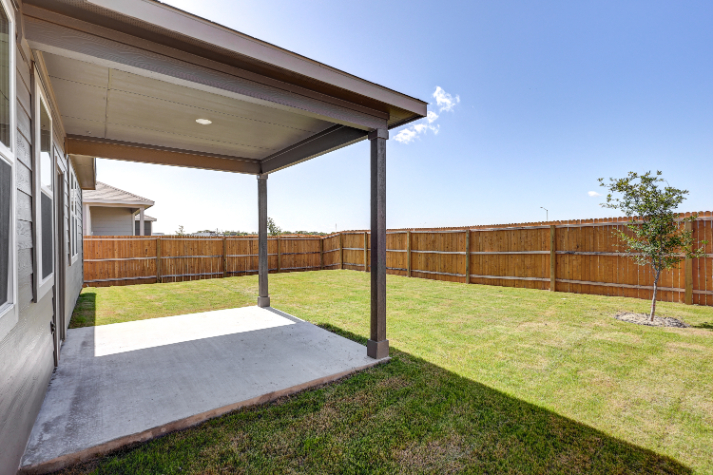 A fenced in yard with a tree and a house with Darwin D. Martin House in the background.