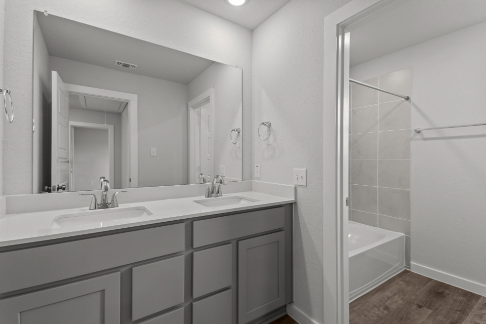 A bathroom with a tub sink and mirror.