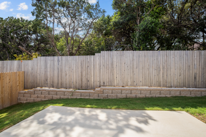 A fenced in yard with a brick wall and grass.