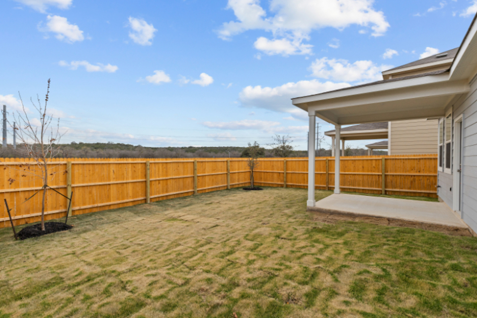 A fenced in yard with a house and trees in the background.