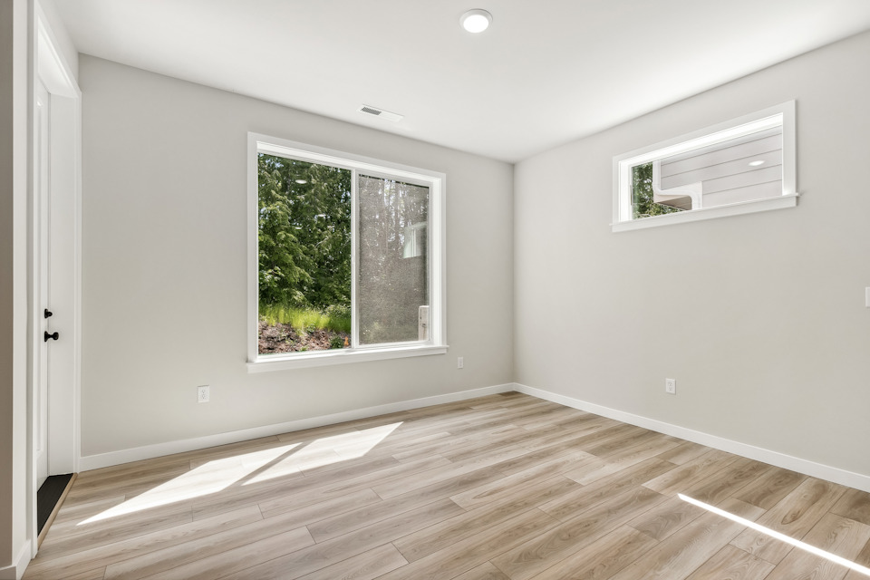 A room with a wood floor and a window with a tree outside.