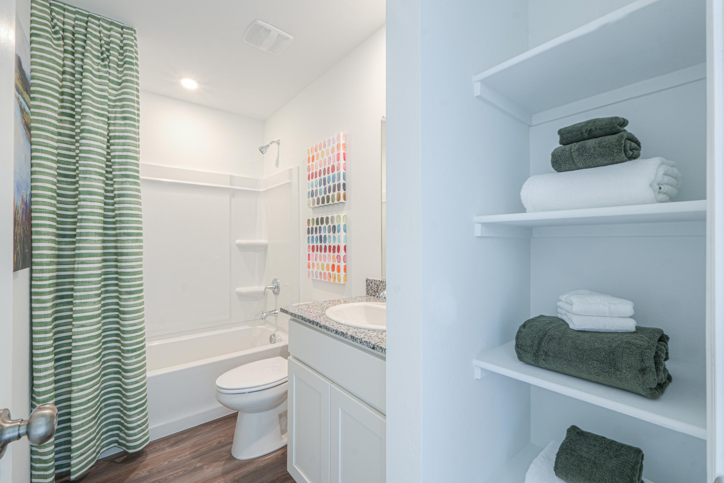 A bathroom with a sink toilet and towels.