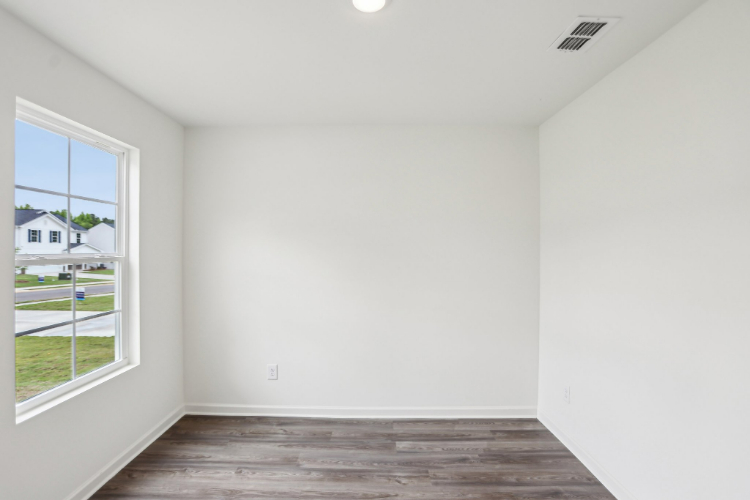 A room with a window and a wood floor.