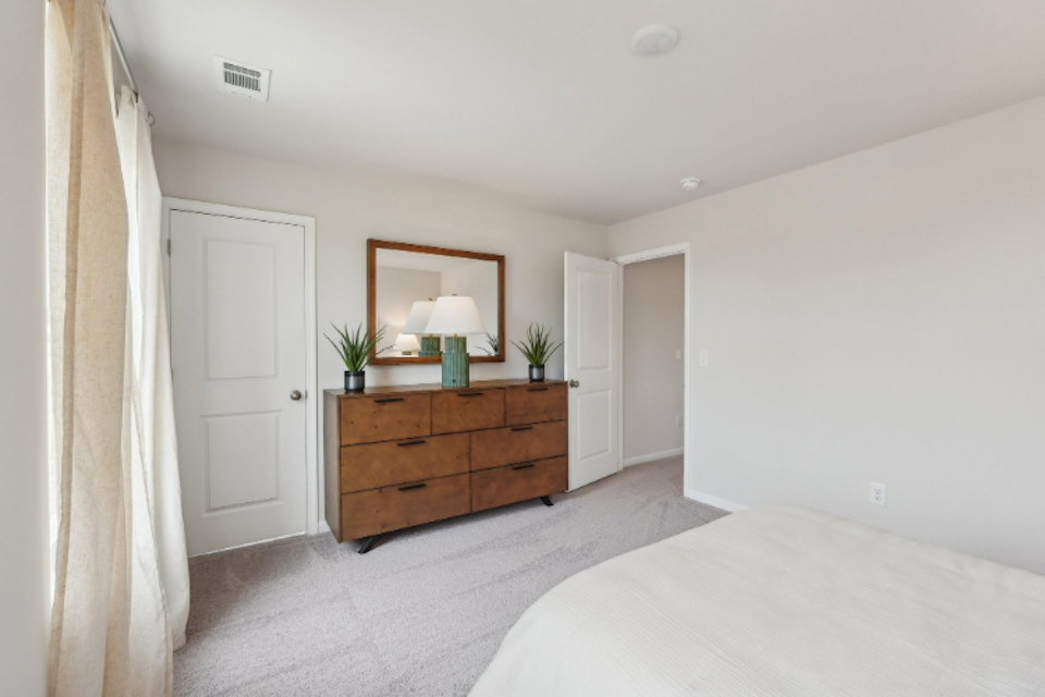 A bedroom with a bed and a dresser.