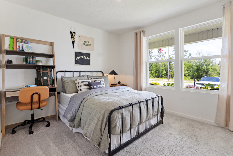 A bedroom with a bed and a chair.